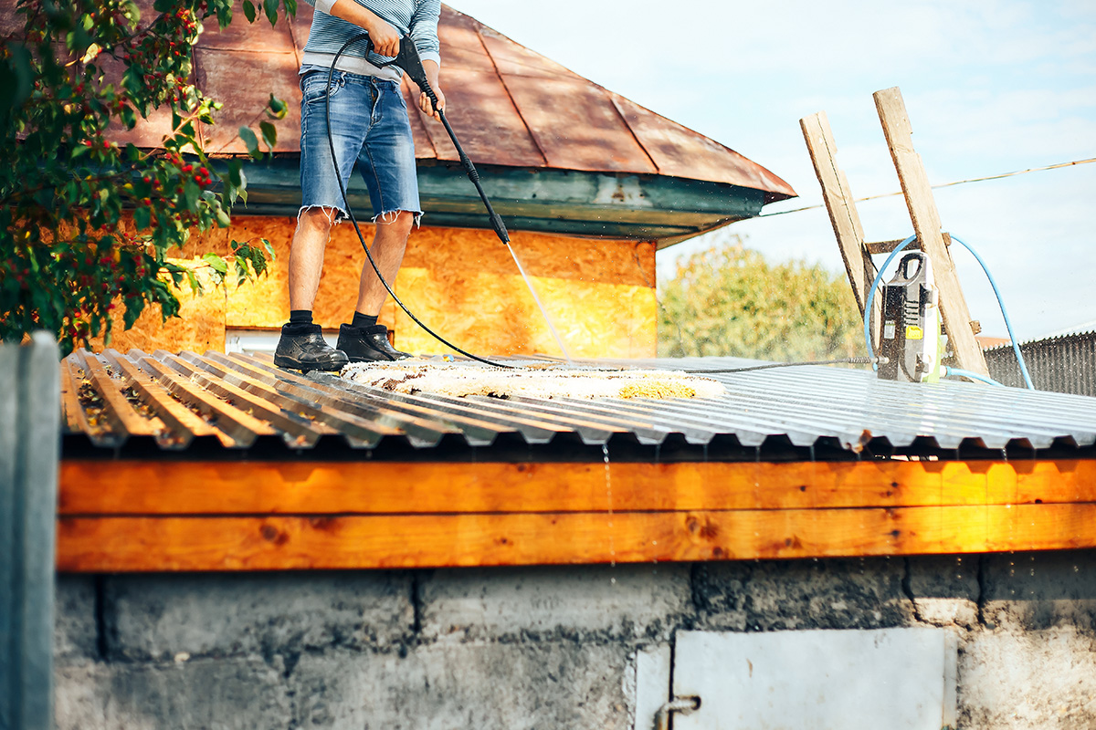 Man cleaning outdoor shed roof