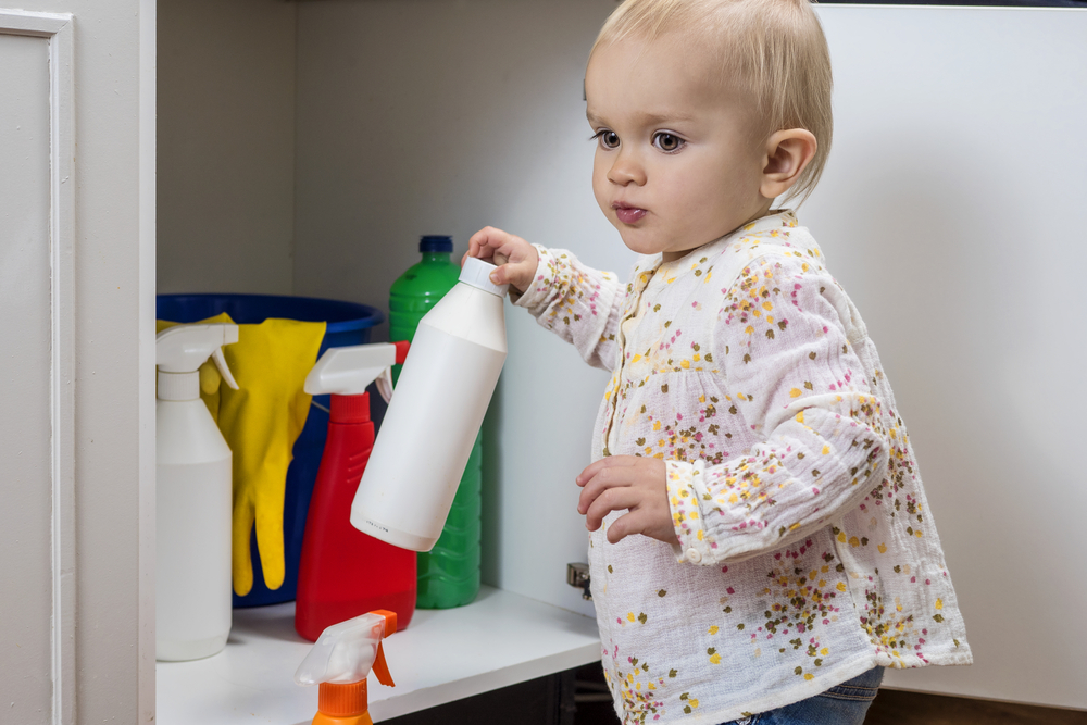 Toddler grabbing household cleaner from cupboard